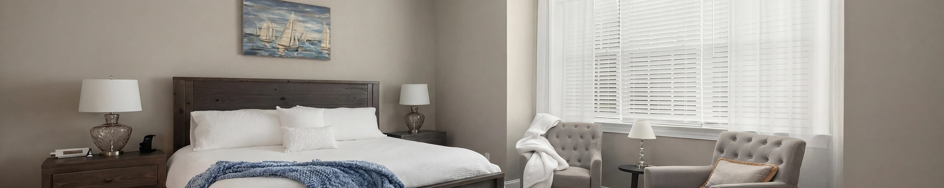 Modern bedroom with bed, chairs, and smart shades.