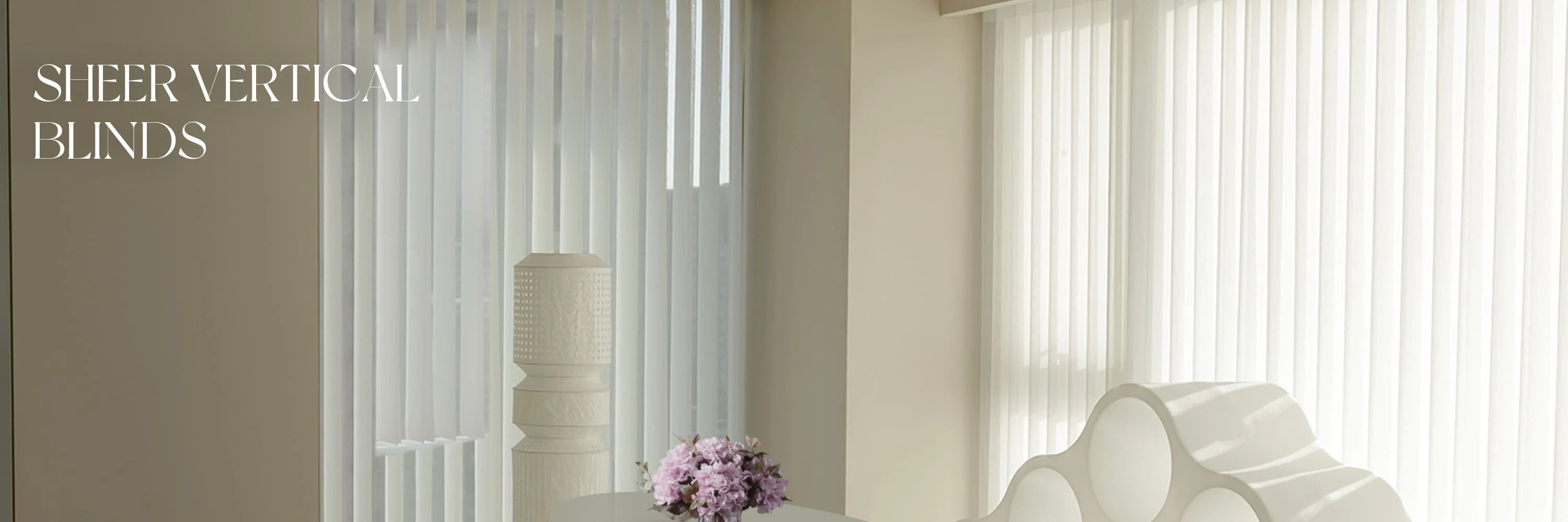 Sheer vertical blinds in a room with a lamp and flowers.