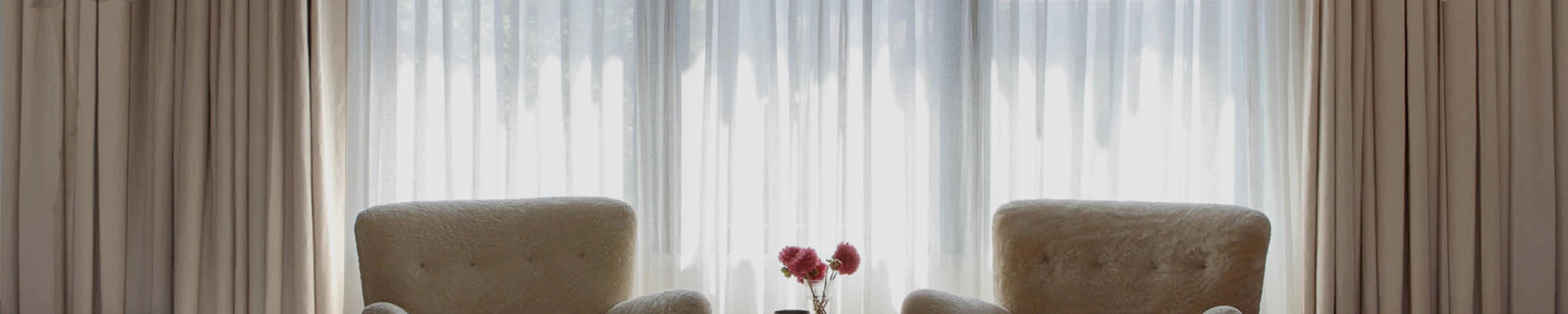 Two brown armchairs in a room with smart curtains.