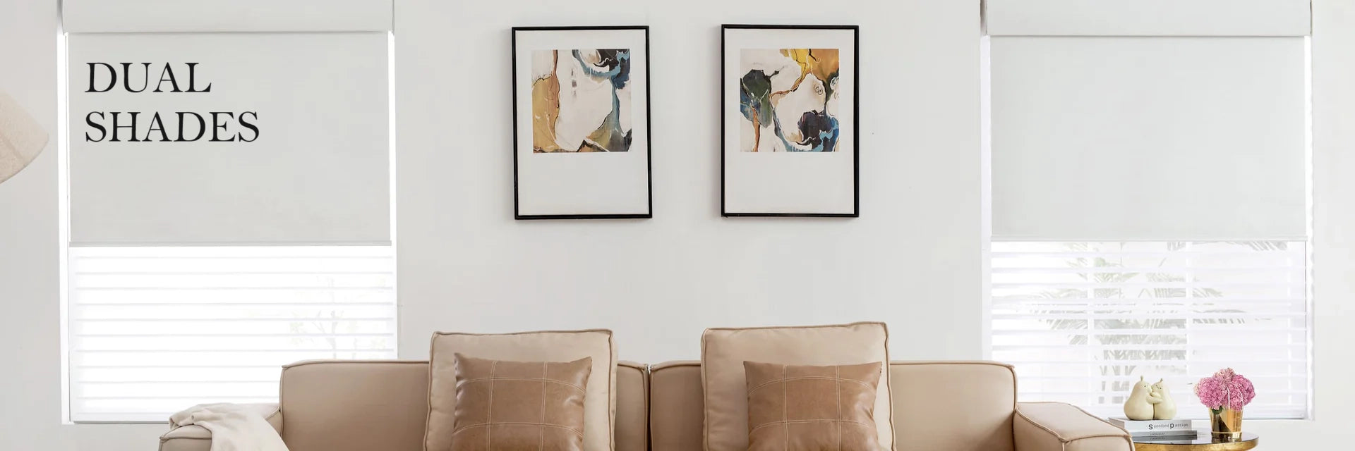 Living room with beige sofa, framed pictures on the wall, and dual shades covering windows.