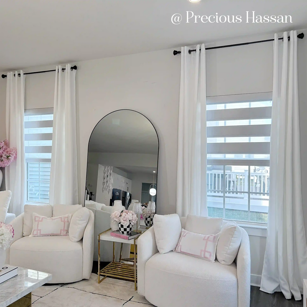 Living room with white furniture, curtains, and zebra blinds.