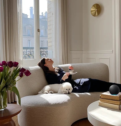 Woman and her dog lying on a sofa in a stylish room with curtain.