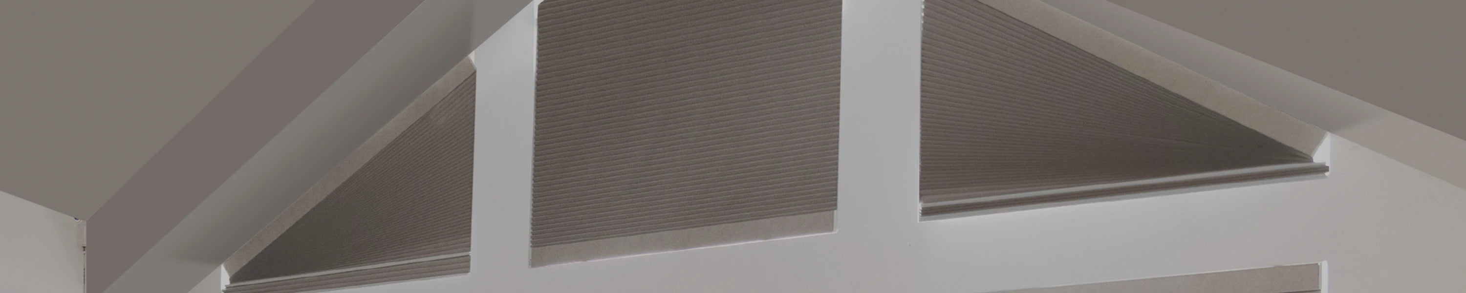 Window with white frame and brown shapped blinds in a room.