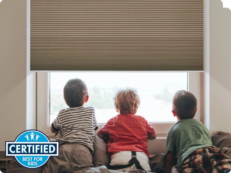 Three children sitting on a window sill looking out a window with a certified logo.
