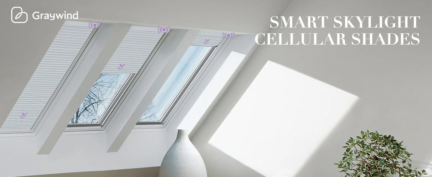 Smart skylight cellular shades on a window with a plant and vase in the foreground.