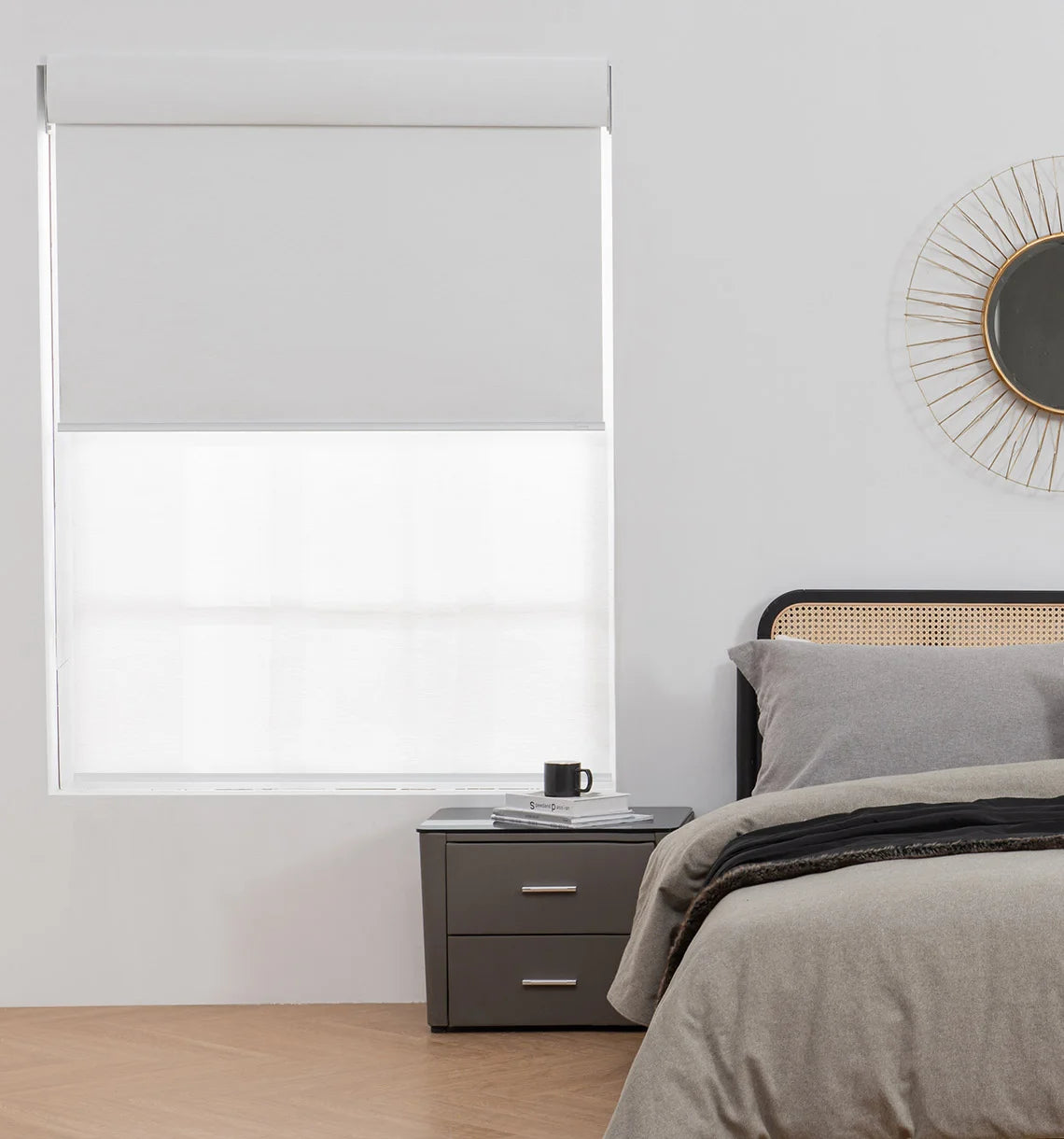 Bedroom with a window covered by dual roller shades, nightstand, and bed.