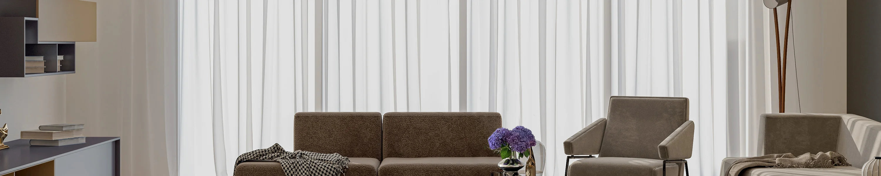 Modern living room with a brown sofa and armchair against a light filtering shades.