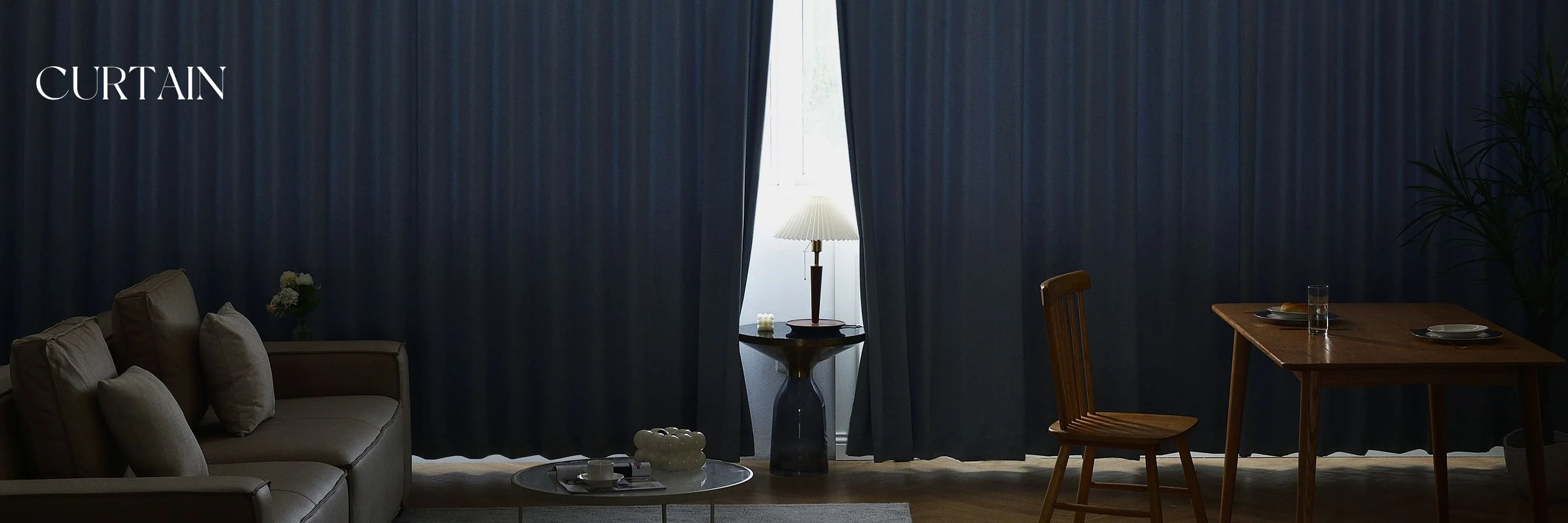 Dark blue curtains in a living room setting with a sofa and table.