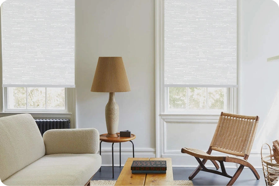 Living room with beige sofa, wooden coffee table, wicker chair, roller shades and lamp.