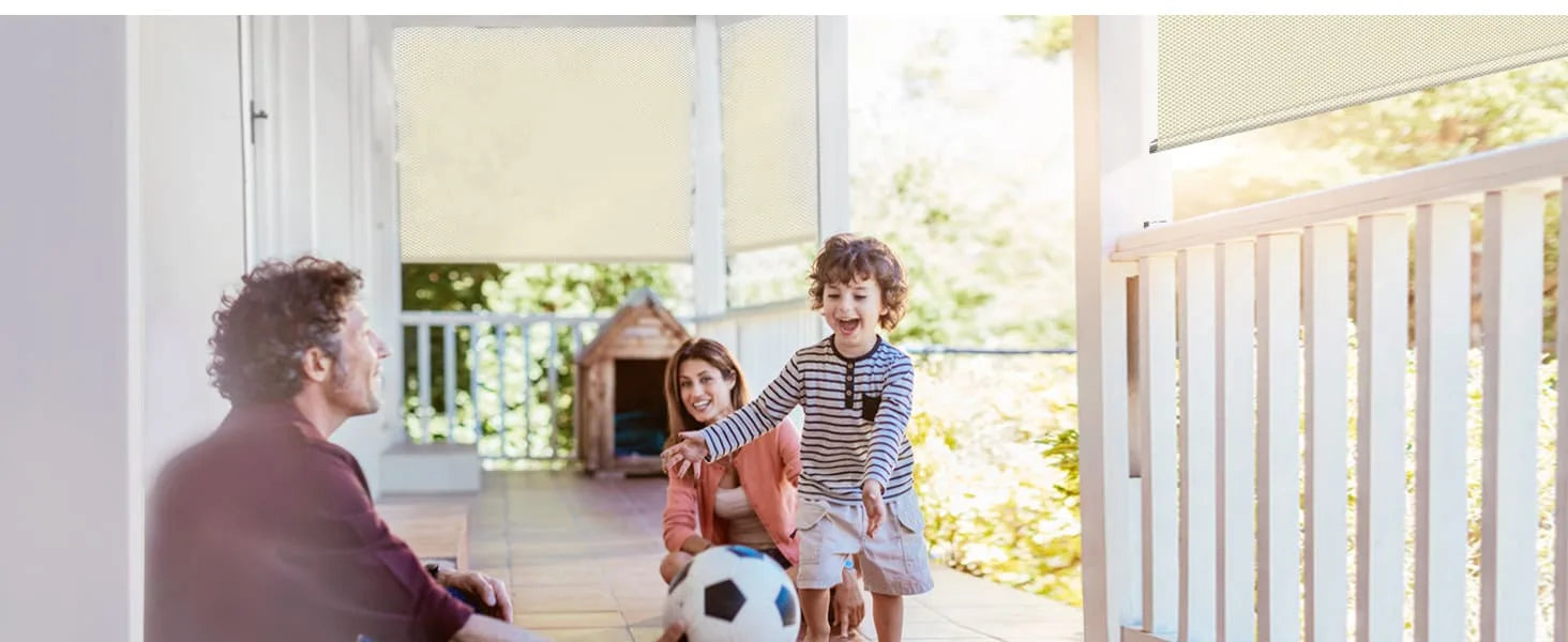 Family with children and a dog on a porch with Graywind Outdoor Shades in the background