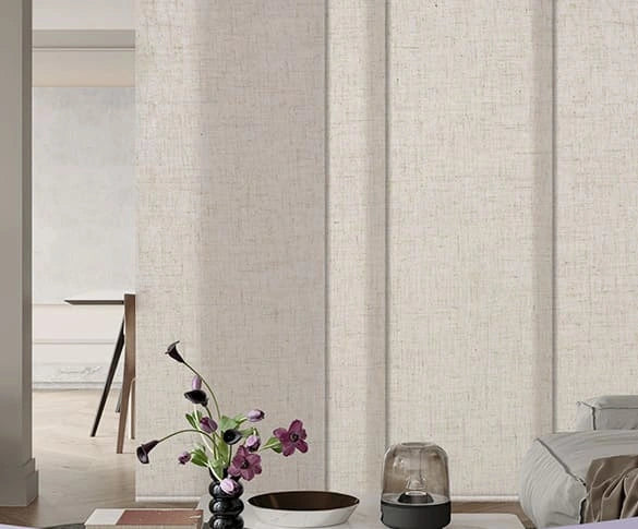 Panel Track Blinds in a room with a vase of flowers and a lamp.