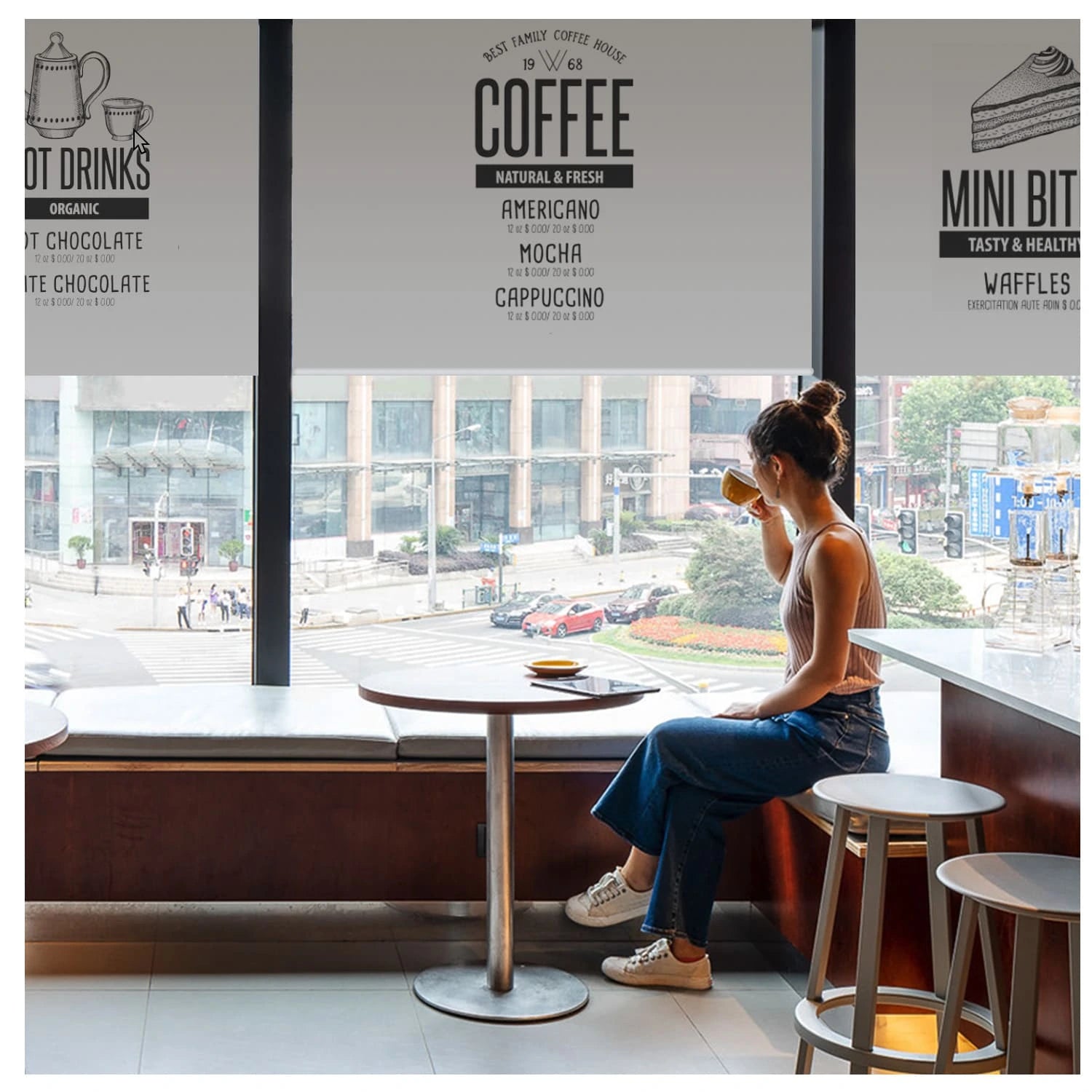 Woman sitting at a table in a coffee shop with printed roller shades