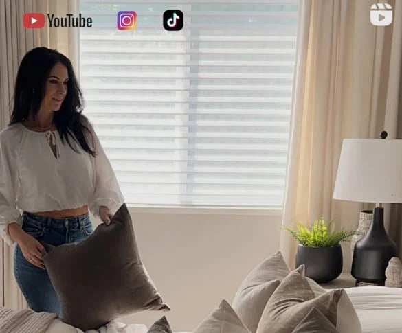 Woman holding a pillow in a living room with decor elements.