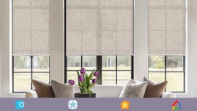 Beige window blinds covering three windows with a vase of purple tulips on a windowsill.