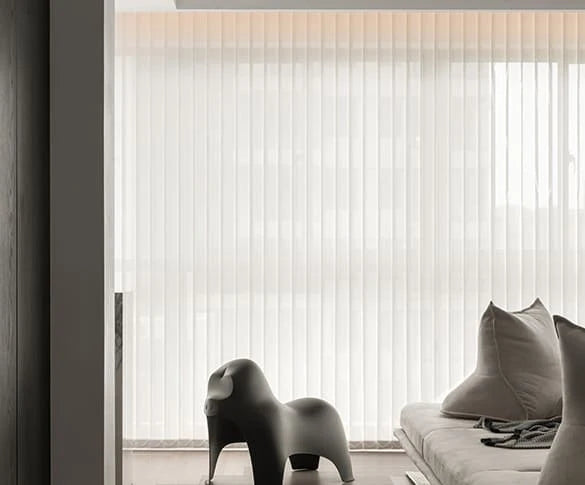 Modern interior with a sofa, decorative pillow, and abstract sculpture in front of a large window with vertical blinds.